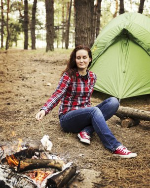 Ormanda kamp. Kız bir hamakta oturur ve t görünüyor