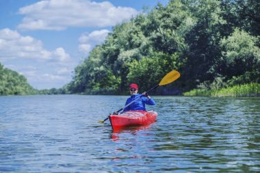 Bir kız nehrin üzerinde bir kayık sallar.