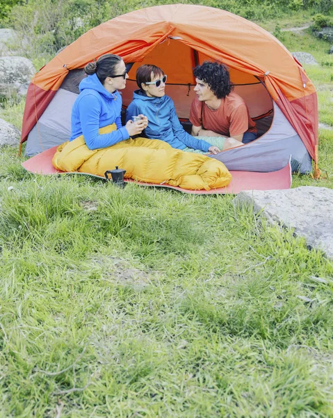 Grupp vänner avkopplande utanför tälten på campingsemester. — Stockfoto