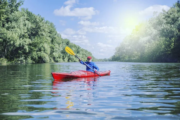 Une fille radeaux sur un kayak sur une rivière par une journée ensoleillée . — Photo