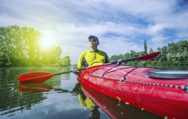 Bir adam bir kayık Nehri üzerinde güneşli bir günde sallar.