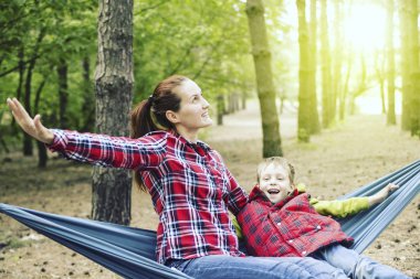 Anne ve oğlu ormandaki bir hamakta oturmuş.