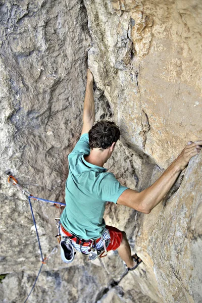 Jeune homme grimpant sur un mur de calcaire avec une large vallée sur le b — Photo