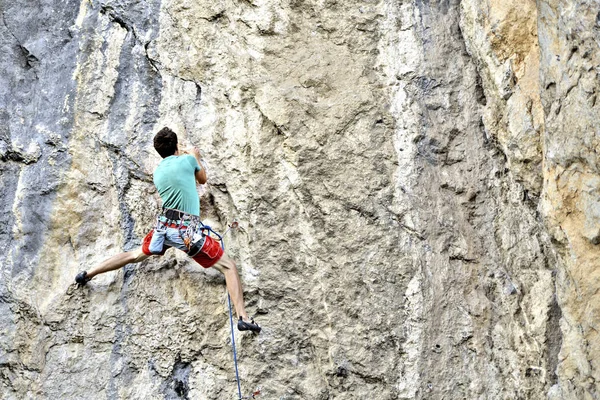 Jeune homme grimpant sur un mur de calcaire avec une large vallée sur le b — Photo