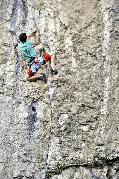 Joven escalando en una pared de piedra caliza con amplio valle en el b — Foto de Stock