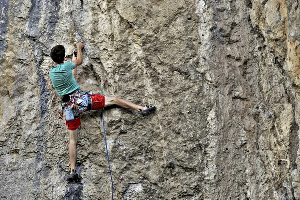 Jeune homme grimpant sur un mur de calcaire avec une large vallée sur le b — Photo