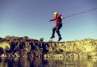 Jump off a cliff into a canyon with a rope. clipart