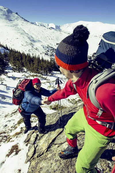 Klimmer helpen teamgenoot klimmen de man met de rugzak bereikt — Stockfoto