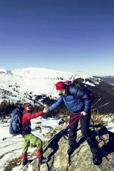 Climber helping teammate climb the man with the backpack reached