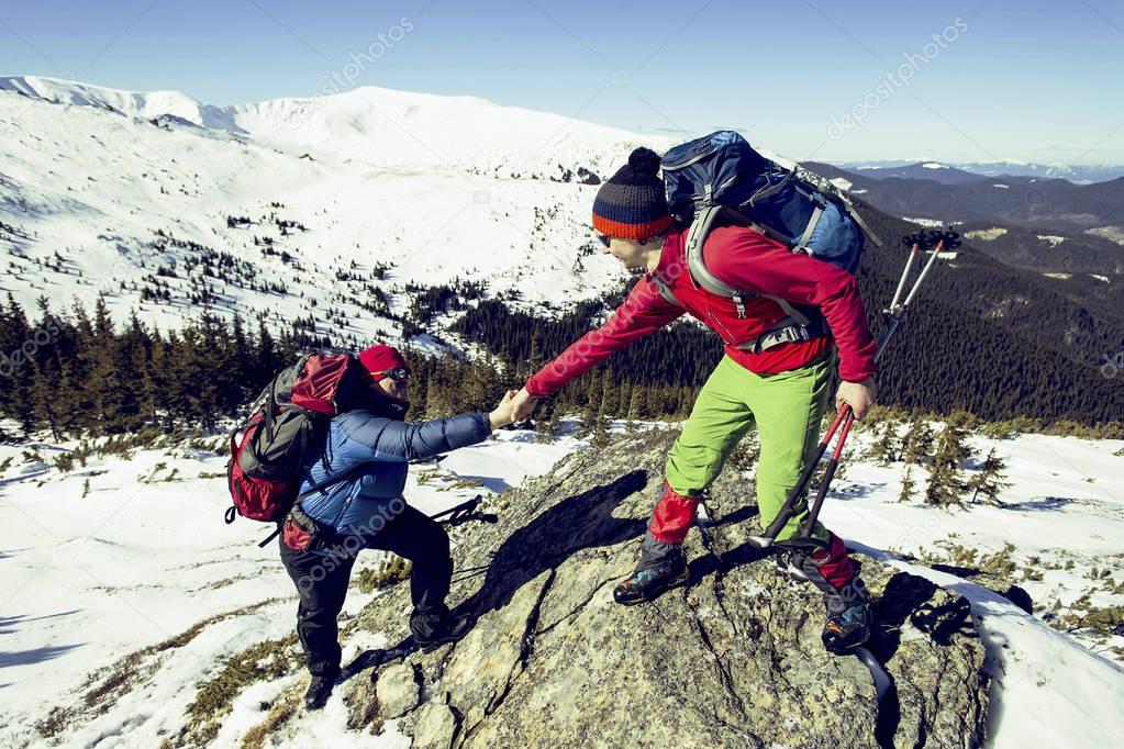 Climber helping teammate climb the man with the backpack reached