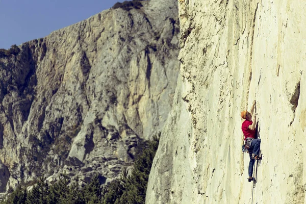 Joven sube a una pared rocosa en un valle con montañas . —  Fotos de Stock