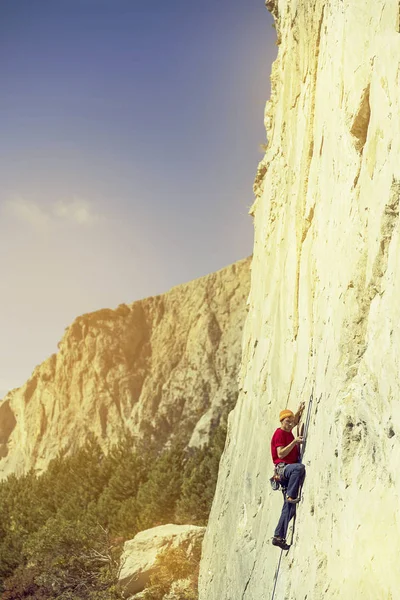 Genç adam bir vadide Dağları ile kayalık bir duvara tırmanıyor.. — Stok fotoğraf