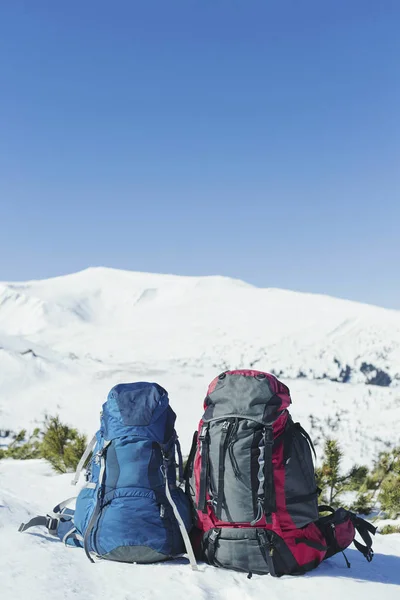 Рюкзаки стоять на снігу на тлі гори — стокове фото