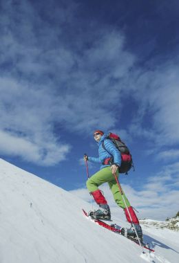 Bir adam dağlarda kışın tırmanıyor..