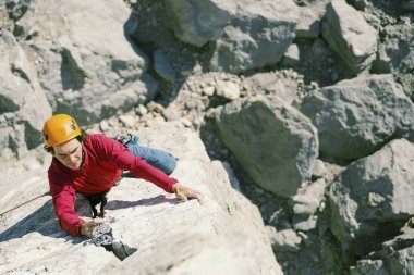 Climber erkeği bir uçurumun tepesine tırmanıyor.