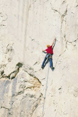 Climber erkeği bir uçurumun tepesine tırmanıyor.