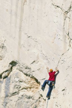 Climber erkeği bir uçurumun tepesine tırmanıyor.