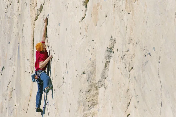 Climber erkeği bir uçurumun tepesine tırmanıyor.
