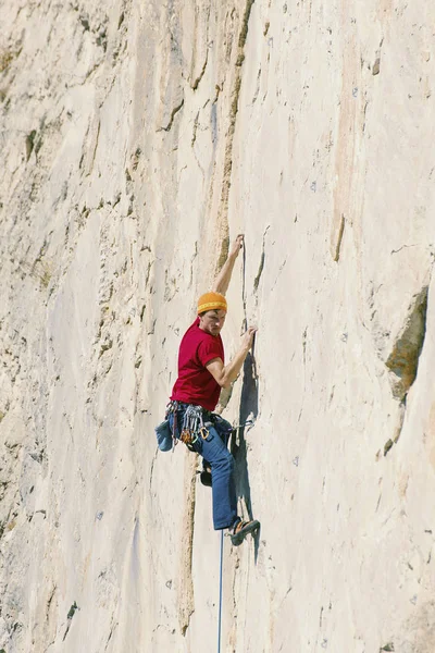Climber erkeği bir uçurumun tepesine tırmanıyor.