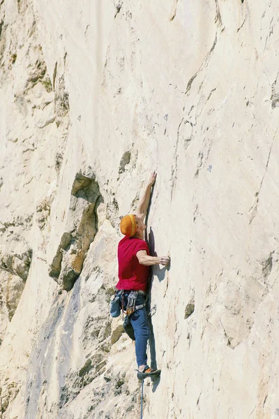Climber erkeği bir uçurumun tepesine tırmanıyor.