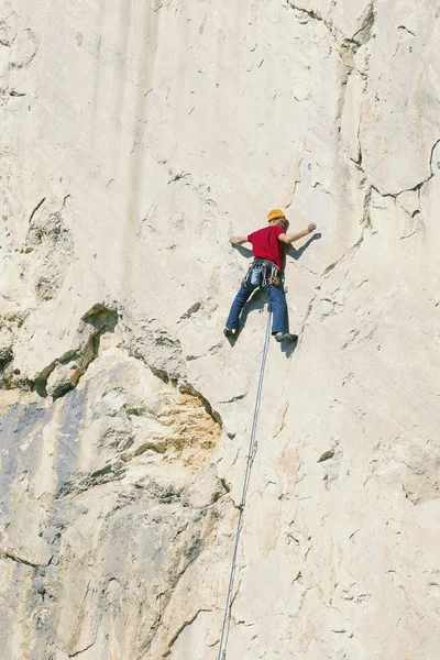 Climber erkeği bir uçurumun tepesine tırmanıyor.