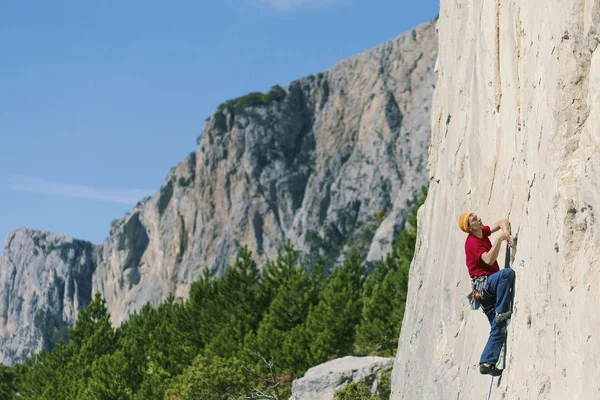 Climber erkeği bir uçurumun tepesine tırmanıyor.