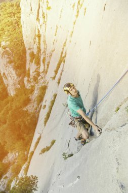 Climber erkeği bir uçurumun tepesine tırmanıyor.