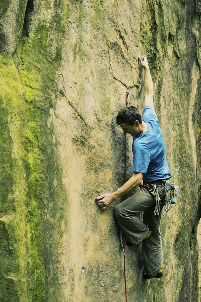 Un grimpeur grimpe une montée vers une falaise . — Photo