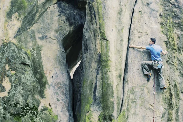 En klättrare klättrar en uppstigning till en klippa. — Stockfoto