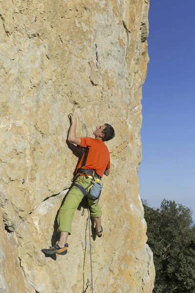 Un hombre escalando rocas sobre el fondo del mar . — Foto de Stock