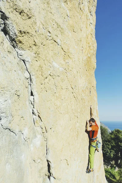 Een man en klimmen op de rotsen tegen de achtergrond van de zee. — Stockfoto