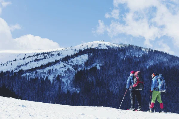 Senderismo de invierno en las montañas en raquetas de nieve con una mochila y — Foto de Stock