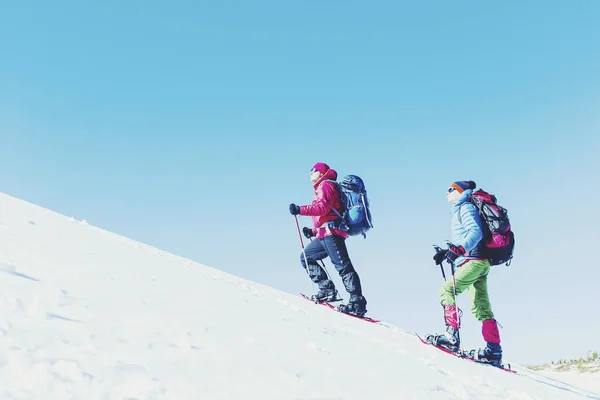 Senderismo de invierno en las montañas en raquetas de nieve con una mochila y — Foto de Stock