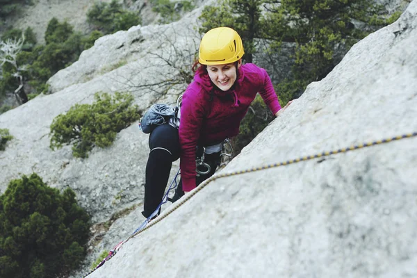 A young woman with a rope engaged in the sports of rock climbing — Stock Photo, Image