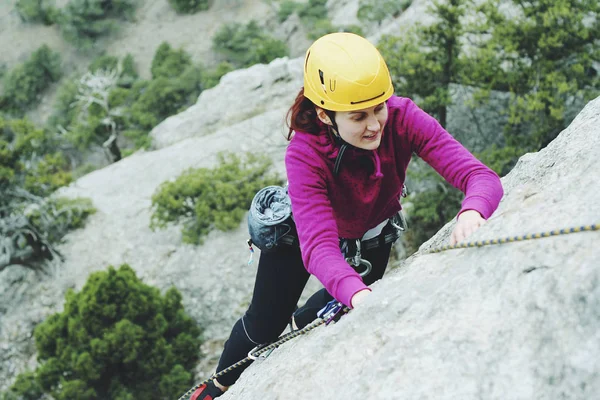 Una giovane donna con una corda impegnata nello sport dell'arrampicata su roccia — Foto Stock