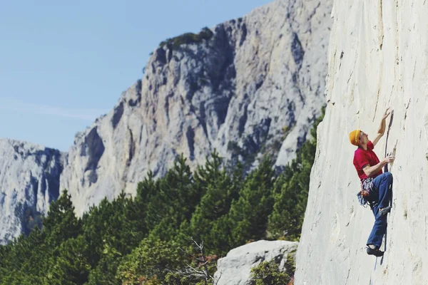 Bergsteiger, der eine herausfordernde Klippe erklimmt. Extremsport klettert — Stockfoto