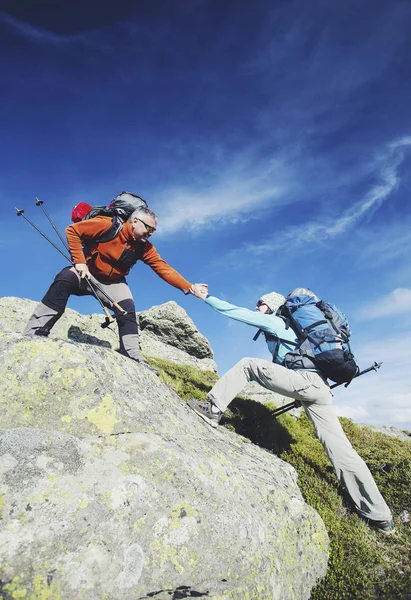 Pareja Hombre y Mujer ayudan a dar las manos escalando montañas rocosas — Foto de Stock