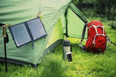 Nehir kıyısında kamp. Güneş paneli üzerinde çadır kilitleniyor.