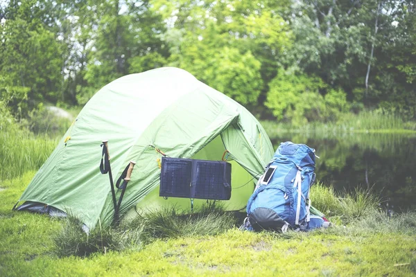 Acampar na margem do rio. O painel solar está pendurado na tenda . — Fotografia de Stock