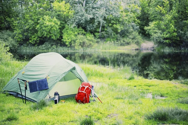 Campeggio sulla riva del fiume. Il pannello solare pende sulla tenda . — Foto Stock