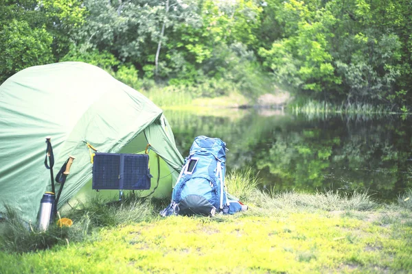 Camping on the river bank. The solar panel hangs on the tent. — Stock Photo, Image