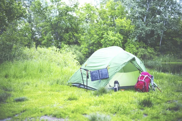 Acampar na margem do rio. O painel solar está pendurado na tenda . — Fotografia de Stock