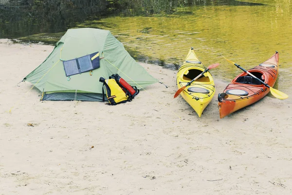 Kanolar üzerinde rafting. Nehir kıyısında bir çadır kampı var..