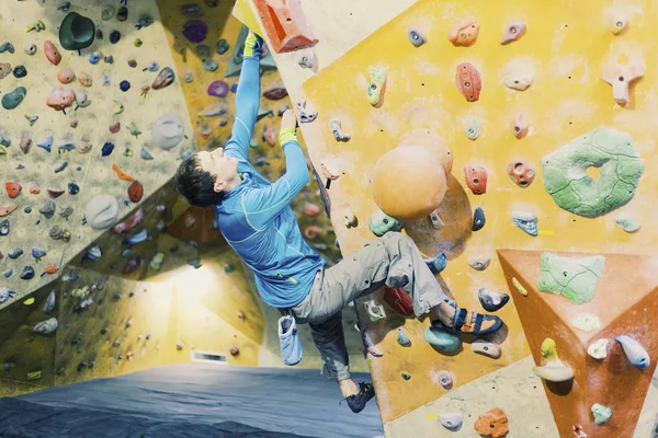 Joven practicando escalada en roca en una pared de roca en el interior . —  Fotos de Stock