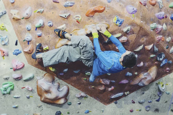 Young man practicing rock-climbing on a rock wall indoors. — Stock Photo, Image