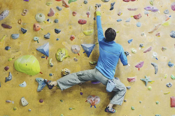 Νεαρός άνδρας εξάσκηση αναρρίχηση σε βράχο τοίχο σε εσωτερικούς χώρους. — Φωτογραφία Αρχείου