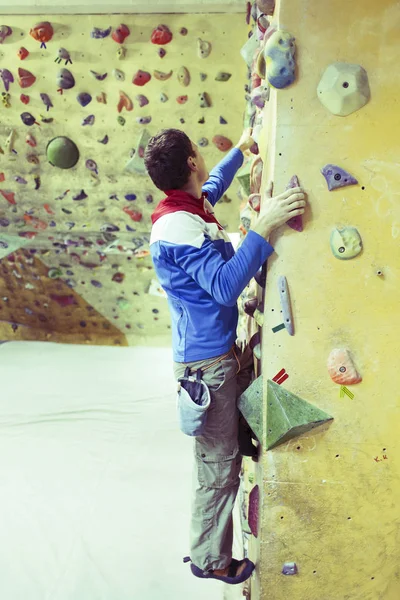 Joven practicando escalada en roca en una pared de roca en el interior . —  Fotos de Stock