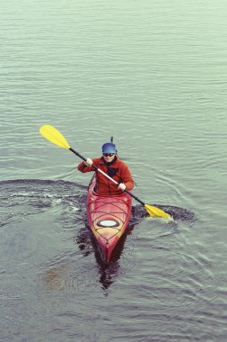 Bir adam nehrin üzerinde bir kayık sallar.