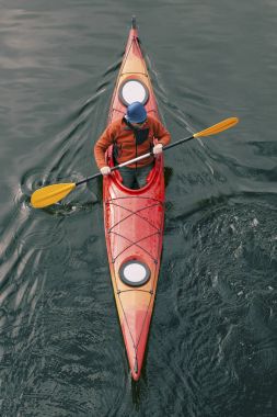 Bir adam nehrin üzerinde bir kayık sallar.