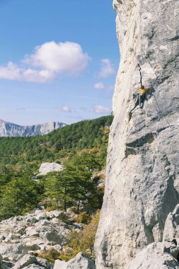 Adam dağcı. Kaya tırmanışçısı kayalık bir duvara tırmanıyor. Adam yapar